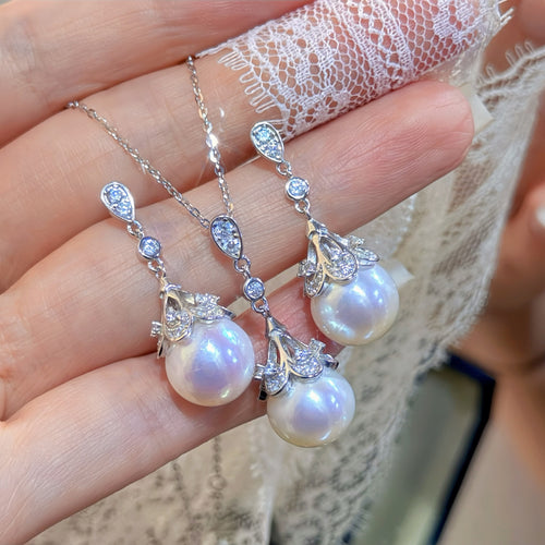 Pearl necklace with silver chain held in hand against lace fabric