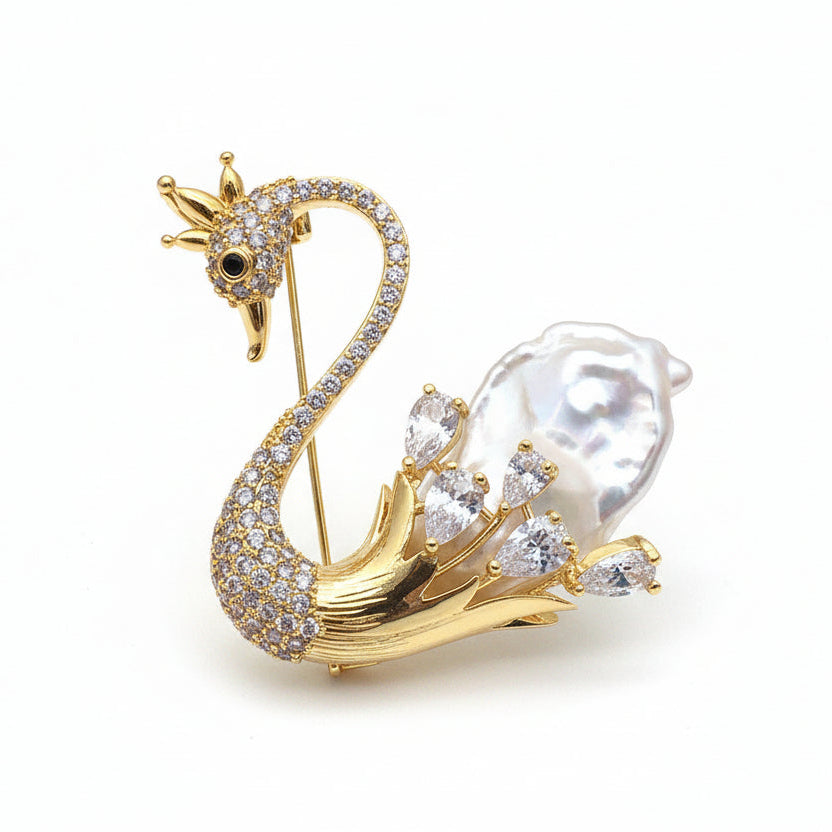 Gold swan brooch with pearls and gemstones on a white background