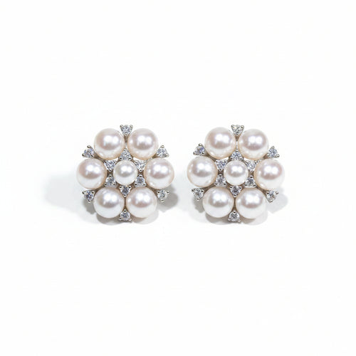 Pearl hair clip held between fingers against a dark background