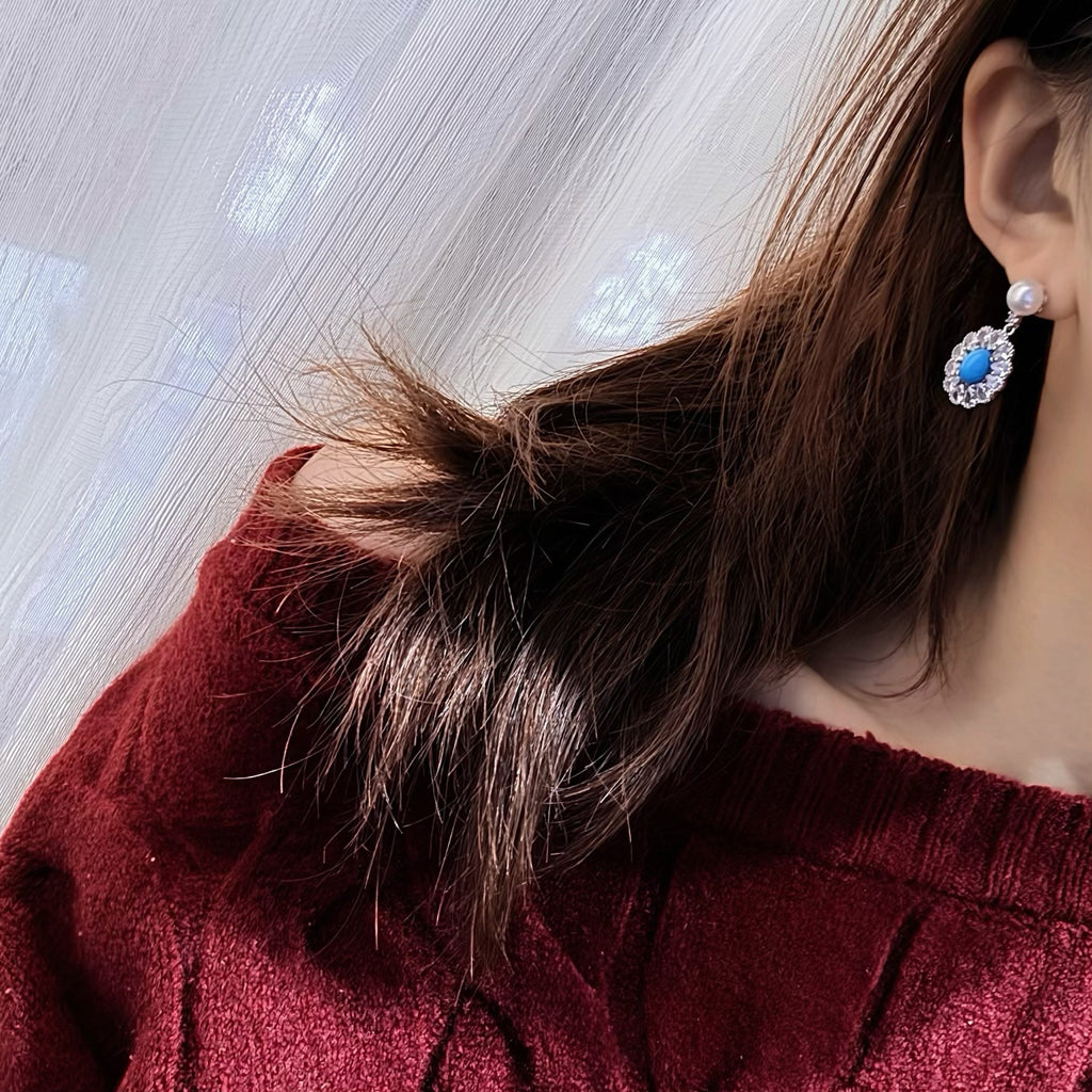 Model wearing pearl and oval turquoise drop earrings