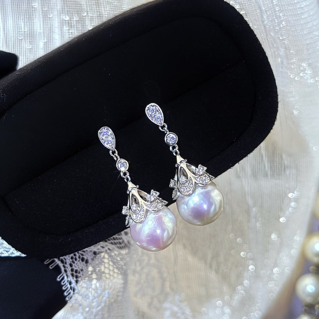 Pearl earrings with silver accents on a black jewelry box