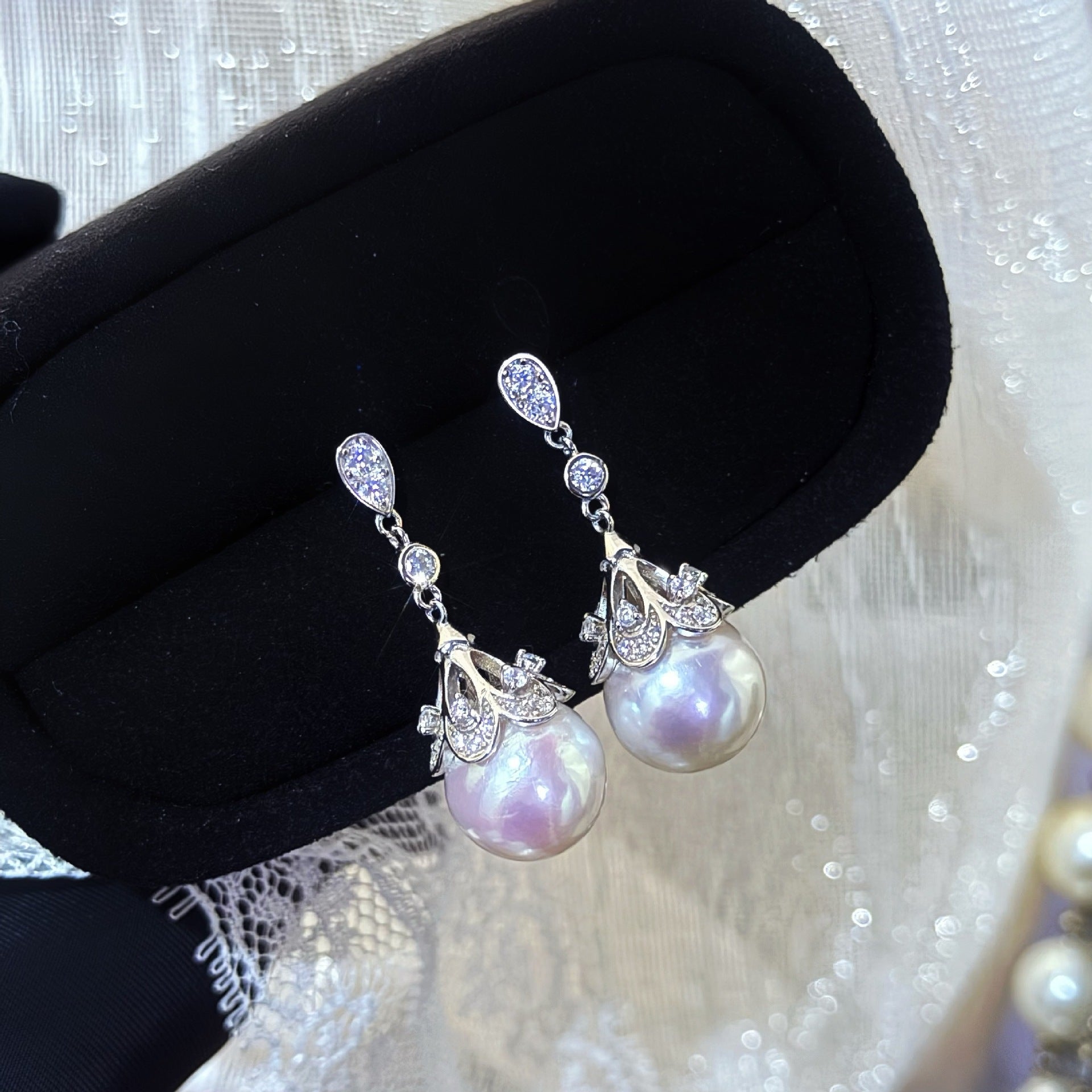 Pearl earrings with silver accents on a black jewelry box