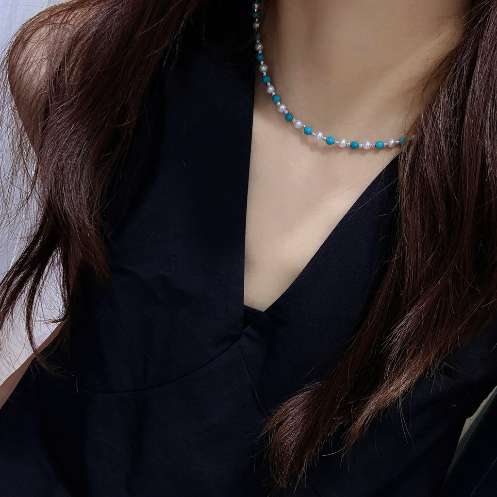 Model wearing pearl and turquoise beaded necklace